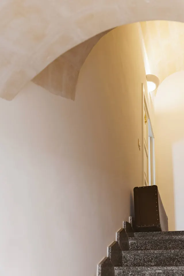 Scala interna della casa con pareti chiare e arco