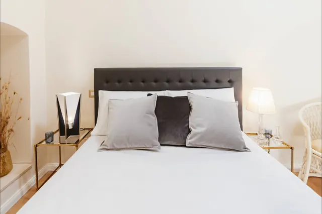 Vista frontale del letto matrimoniale con cuscini e comodini