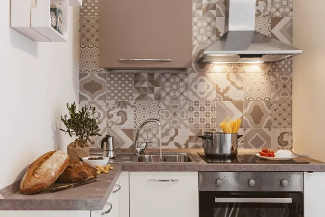 Cucina con piano a induzione, forno e rivestimento decorato