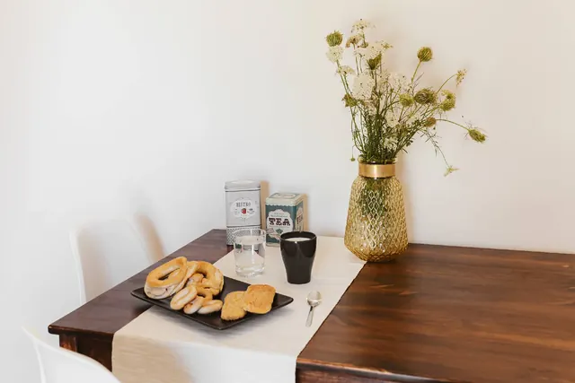 Tavolo in legno apparecchiato con tazze, biscotti e fiori